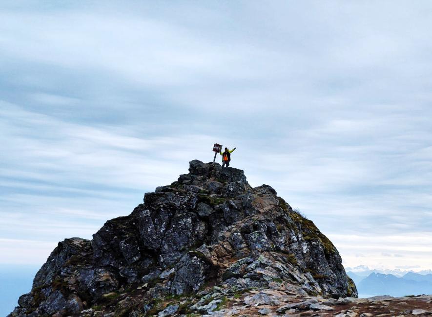On a mountain top with a flag, a symbol of adventure and perseverance